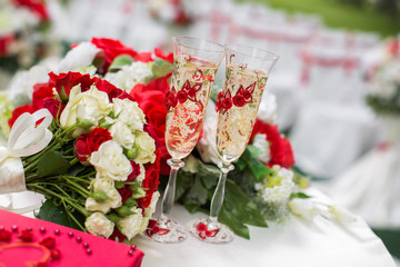 The champagne glasses. Wedding ceremony outdoors. Bouquet with red flowers.