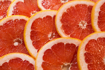 Bright red background with juicy slices of grapefruit. Healthy food background.