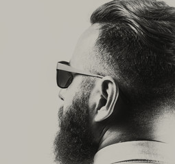 Portrait of a bearded man in sunglasses, with a stylish haircut. Black and white.