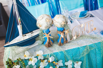 The table in the restaurant for a wedding in a marine style using fresh flowers, boats and nets
