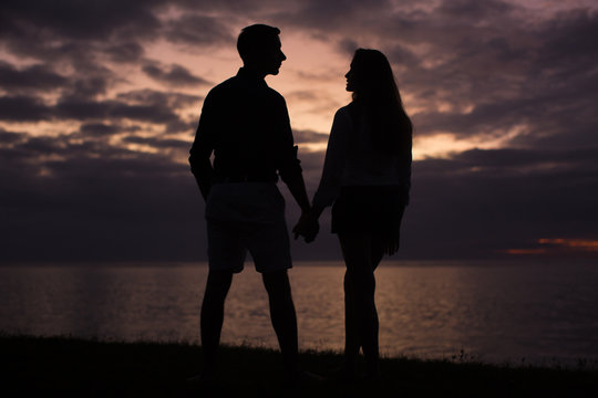 Silhouette of a young couple at sunset on the beach near the ocean