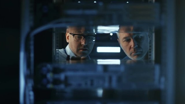 In Data Center Two Server Technicians Install Additional Hardware into Server Rack. Shot on RED EPIC-W 8K Helium Cinema Camera.