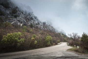 Mountain road in foggy day, rainy landscape
