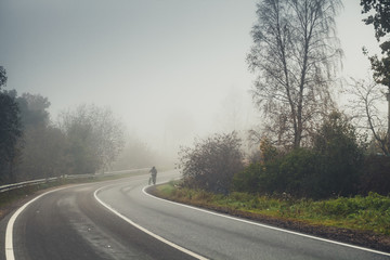 Empty rural road turn in autumn foggy morning