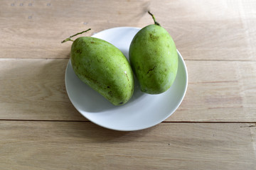 Raw mangoes on white dish