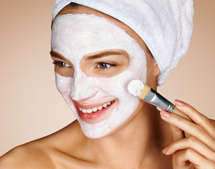 Woman with soothing facial mask. Close up of young woman on beige background. Beauty procedures skin care concept