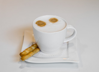Cup with cappuccino and salted stics.