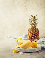 Fototapeta na wymiar Retro style toned photo of homemade frozen pineapple juice popsicles. Summer food concept with copy space.