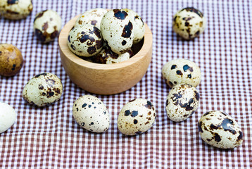 Obraz na płótnie Canvas Quail eggs - Quail eggs in a wooden bowl on old brown wooden surface background, selective focus.