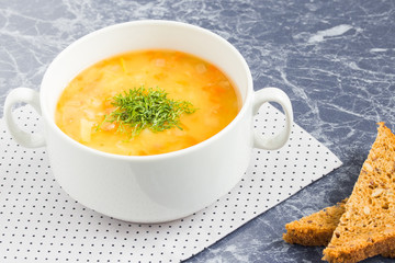 Pea soup with chopped dill in a white bowl on a marble table