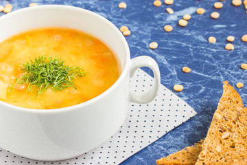 Pea soup with chopped dill in a white bowl on a marble table