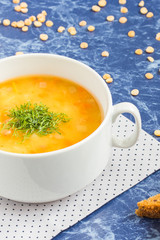 Pea soup with chopped dill in a white bowl on a marble table