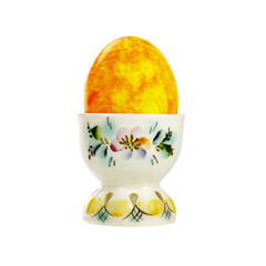 Yellow Easter egg in a porcelain holder isolated on white background