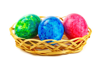 Red, green and blue Easter egg in basket on a white background