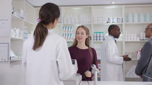  Team of staff working & serving customers in a chemist shop.