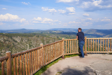 Hombre joven admirando el paisaje desde el mirador de Los Balcones de Madrid en Ourense