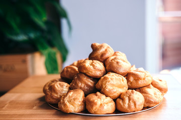 Traditional French dessert profiteroles pastry or eclair on plate. Desserts for party with space for text.