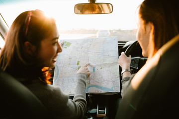 Lost with map two young Asia woman friends in car enjoy road trip