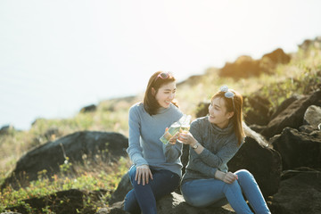 summer, holidays, vacation, happy people concept - smiling Asia girlfriends with bottles of beer or non-alcoholic drinks