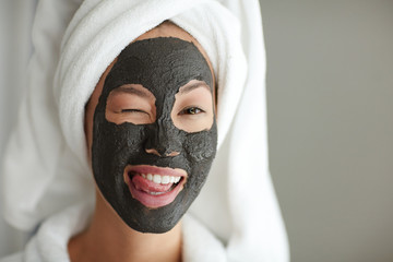 Flirty girl winking while having purifying mask
