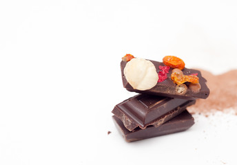 Chocolate pieces with nuts and berries on white