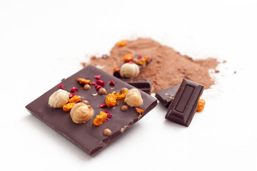 Chocolate pieces with nuts and berries on white