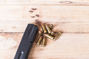 Background of 9 mm pistol gun and bullets strewn on the wood.