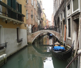 Fototapeta na wymiar Gondola in narrow Venetian canal, characteristic buildings and bridge, Italy