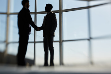 Fototapeta na wymiar Outlines of two handshaking businessmen striking deal