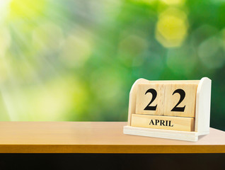 Wooden calendar on wooden desk show the date of April 22 , earth day green bokeh background