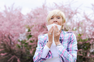 Vibrant blonde middle aged woman sneeze - spring allergies