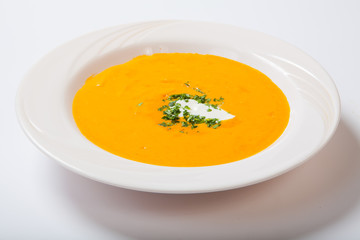 Homemade pumpkin soup with cream with spices on white plate