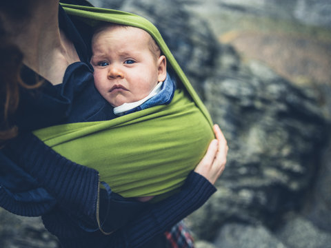 Young mother with baby in sling outdoors