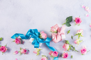 Gift box with blue satin bow and rose flowers on gay