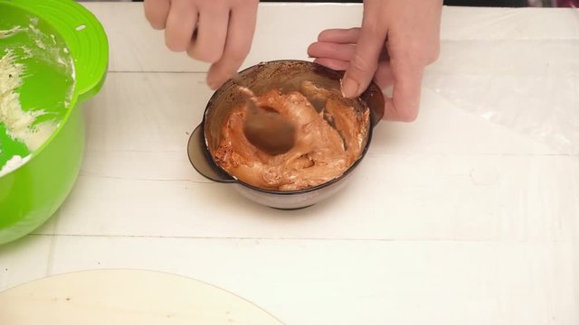 Woman's hands stirring pich cream for a cake in the bowl closeup