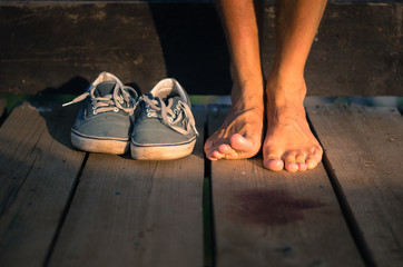 Old man's sneakers around with naked male legs on a wooden background