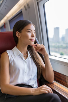 Woman enjoying view in train commute. Woman relaxing enjoying view during morning commute. Business class seat in train. Asian businesswoman pensive looking out the window in travel transport.