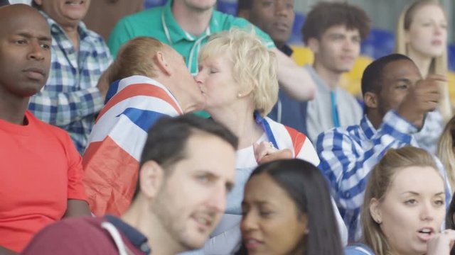  Affectionate mature couple in crowd at sports event draped in British flag