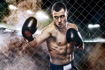 Sportsman muay thai boxer fighting in boxing cage. Background with lights and smoke. Copy Space....
