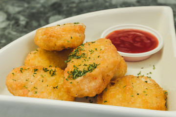 Close up of Crispy chicken nuggets with tomato sauce.