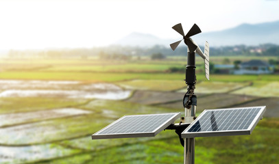 Smart agriculture and smart farm technology concept. Revolving vane anemometer, a meteorological instrument used to measure the wind speed and solar cell system with rice field background. - obrazy, fototapety, plakaty