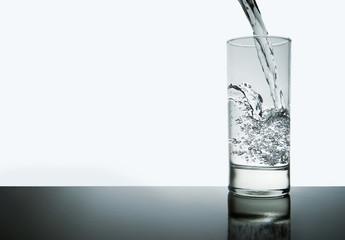 water splashing from glass with copyspace, isolated and blue toned
