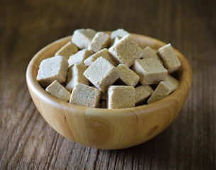 Sugar cubes in wood bowl on wood table