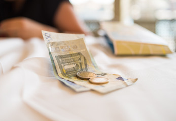 Two euro banknotes and coins lie on a white tablecloth payment the delivery of a breakfast lunch