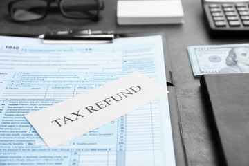 Paper sheet with text TAX REFUND and documents on table