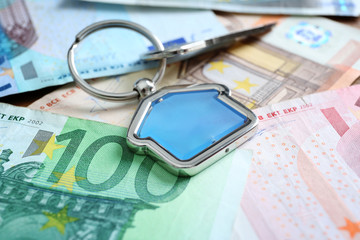 Savings concept. Key with trinket on money