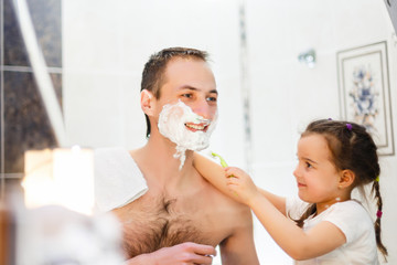 happy father and daughter having fun with shaving foam in the bathroom