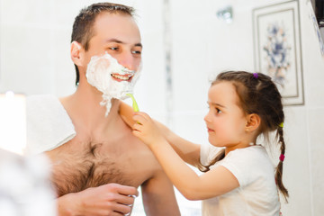 happy father and daughter having fun with shaving foam in the bathroom