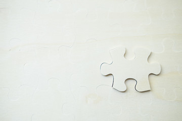 Obraz premium white jigsaw/puzzle whit one gap, over black wooden table background, symbol of problem solving