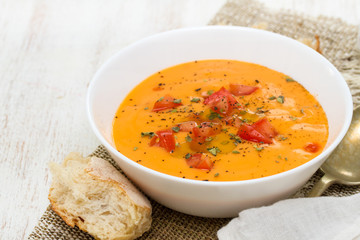 tomato soup in white bowl on wooden background